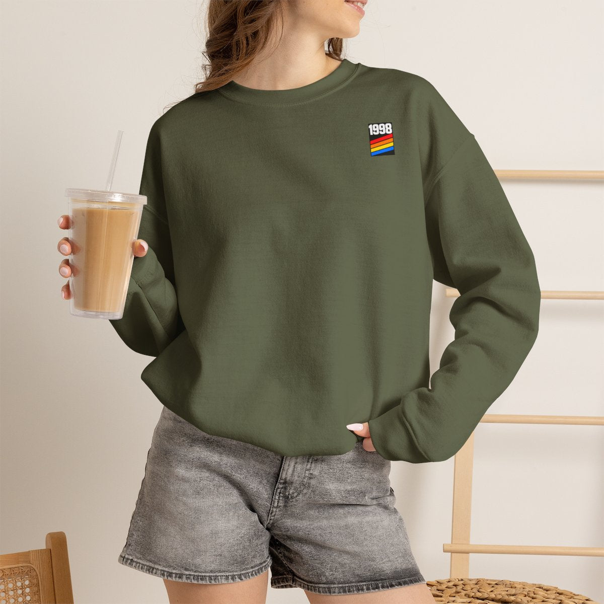 Femme portant le sweat 1998 vert militaire, logo quatre bandes côté cœur